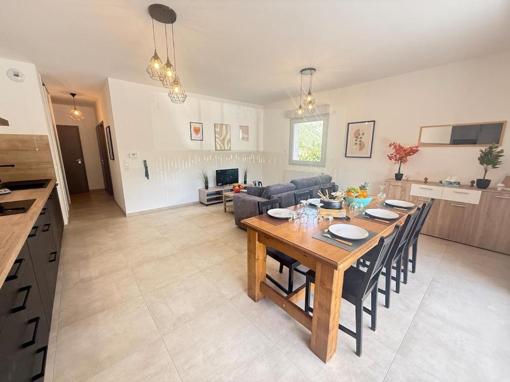 a kitchen and living room with a wooden table and chairs at Le Moulin Balcon Proche Centre Calme in Saint-Jean-de-Maurienne