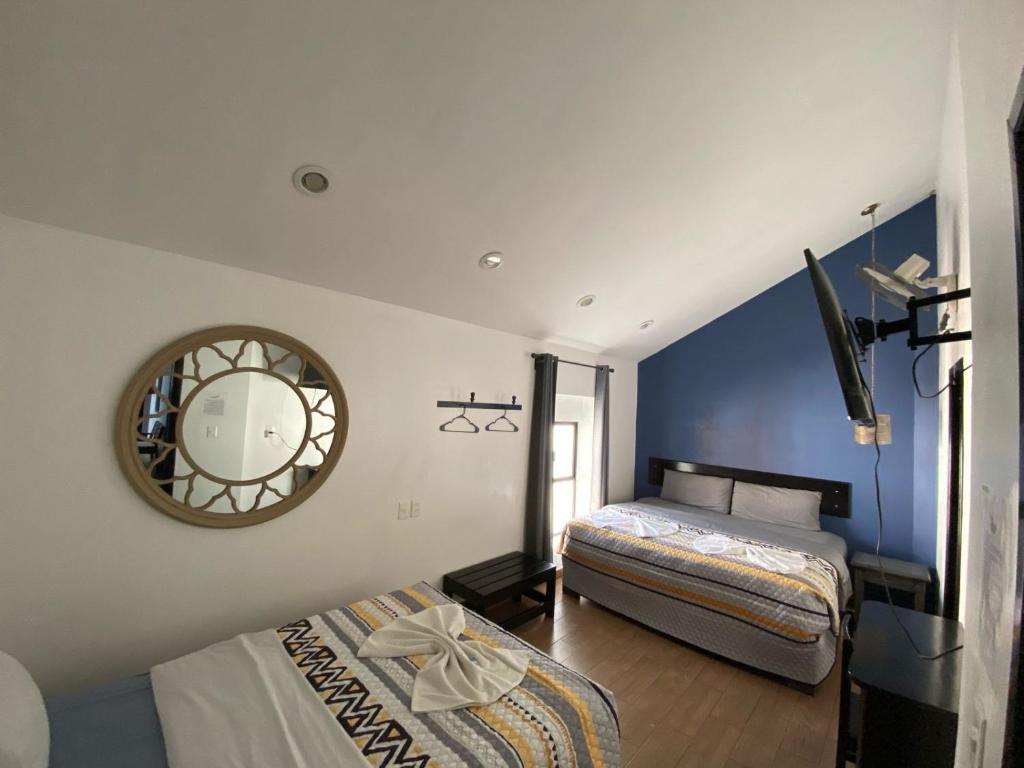 a bedroom with two beds and a mirror on the wall at Hotel Santo Domingo in Comitán
