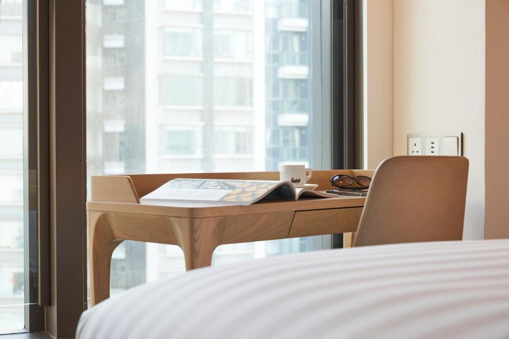 a desk in a room with a bed and a desk with a window at Y Hotel Hong Kong in Hong Kong