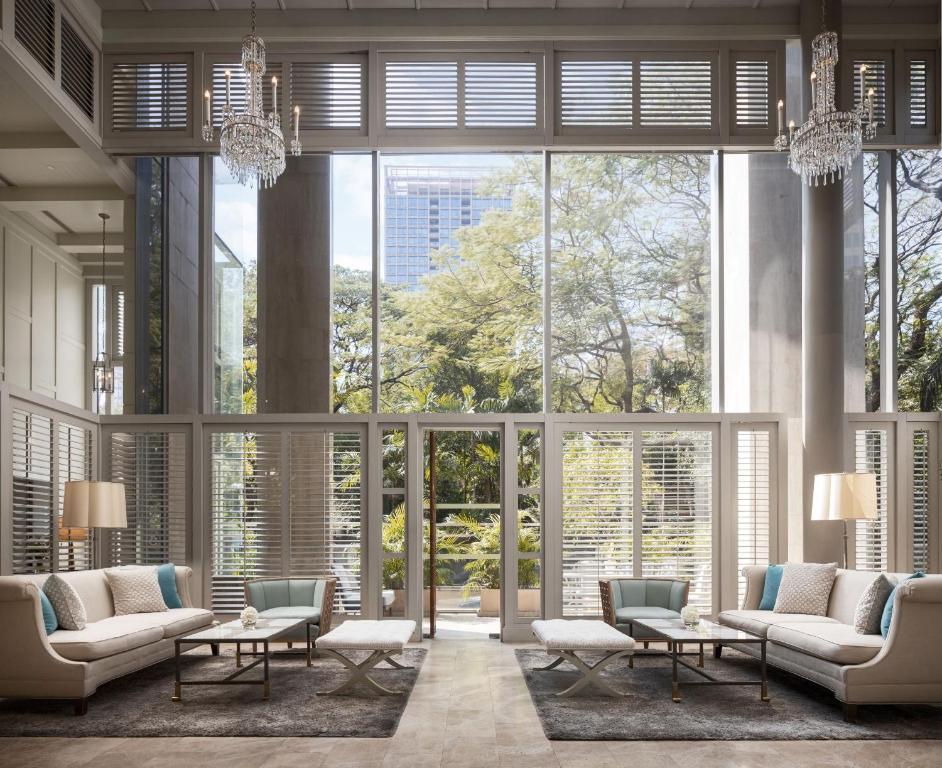 A grand lobby lounge with chandeliers, sofas, and tall garden-facing windows.