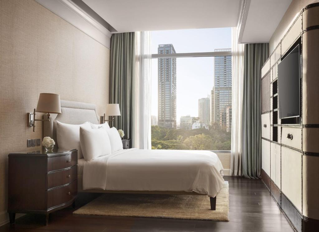 A bright bedroom with a large window, upholstered bed and built-in media wall.