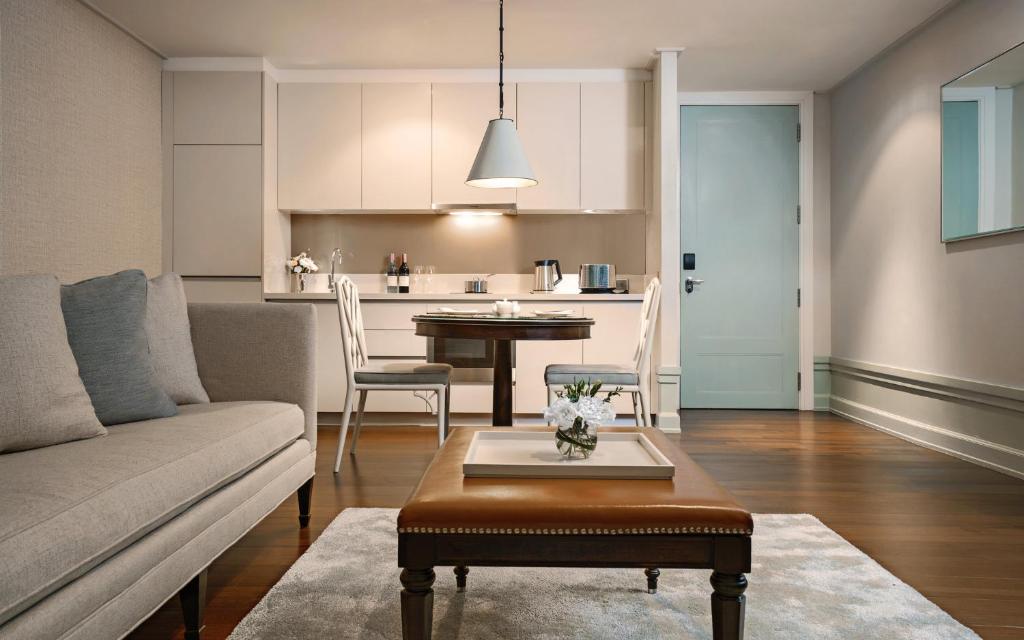 A compact living area with a sofa, coffee table, dining table, and kitchenette.