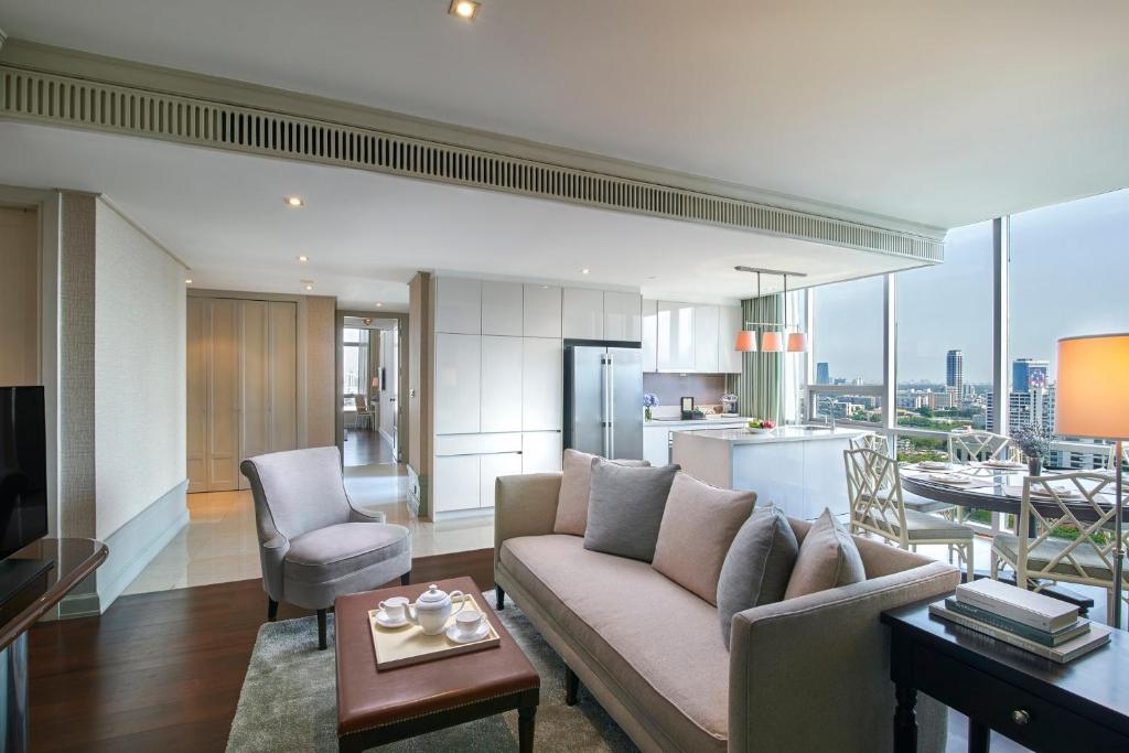 An open-plan living area includes a sofa, armchairs, dining table, kitchen, and broad skyline windows.