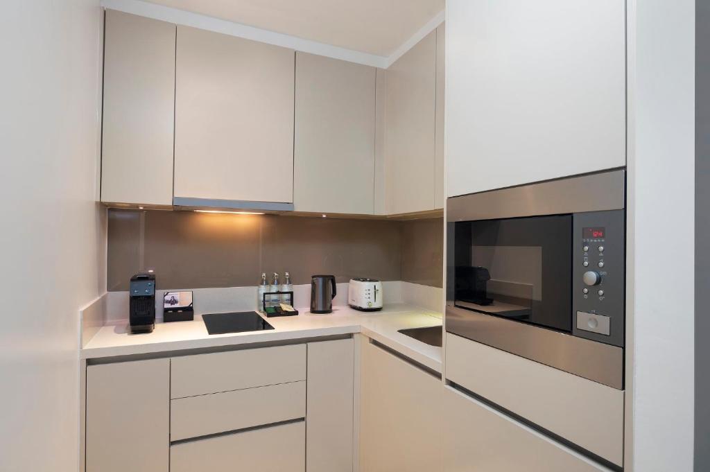 A compact, modern kitchenette with a microwave, induction hob, kettle, and coffee machine.