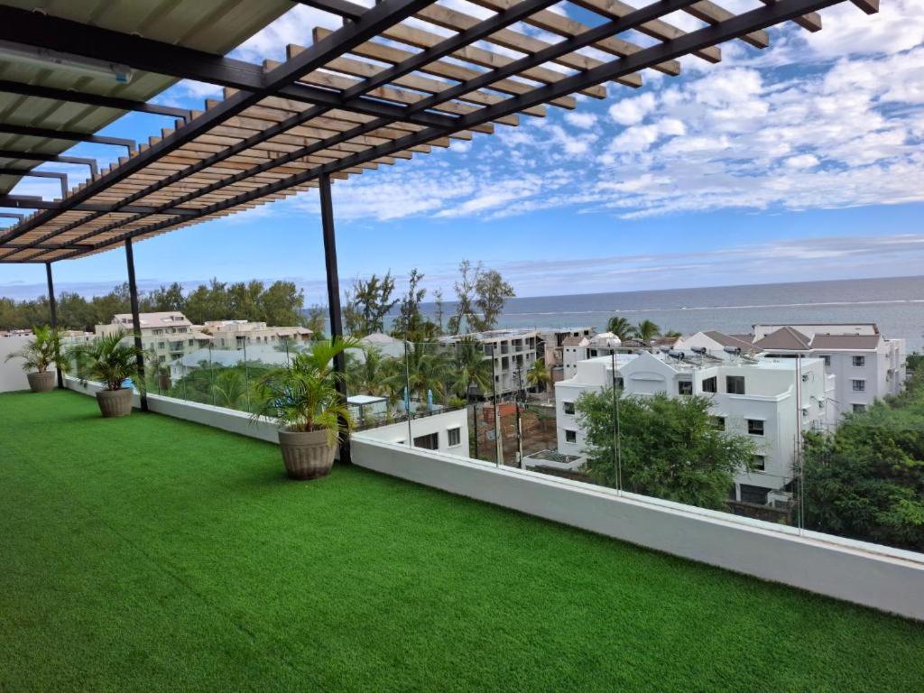 Un balcón con césped verde y edificios blancos. en Azuria Horizon Beach Apartment, en Flic en Flac