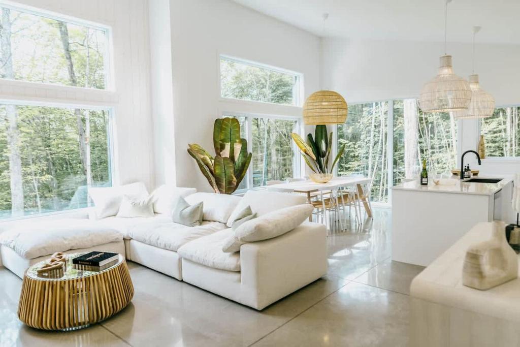 a white living room with a white couch and a table at Zen House 5 - Villas & Spa in Lac-Superieur
