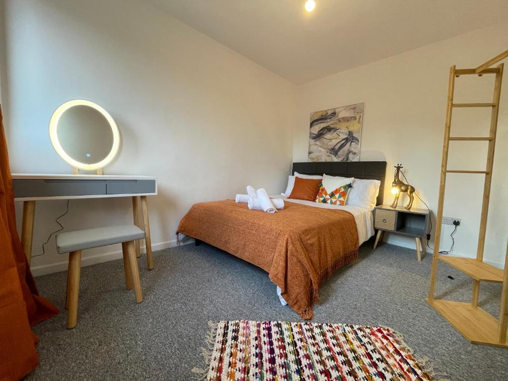 een slaapkamer met een bed met een spiegel en een bureau bij Skylounge Stays in Luton