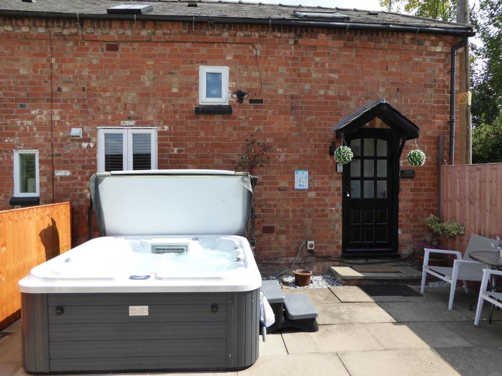 a hot tub on a patio in front of a brick building at Juliet Cottage HOT TUB Sleeps 3 Singles or Double in Stratford-upon-Avon