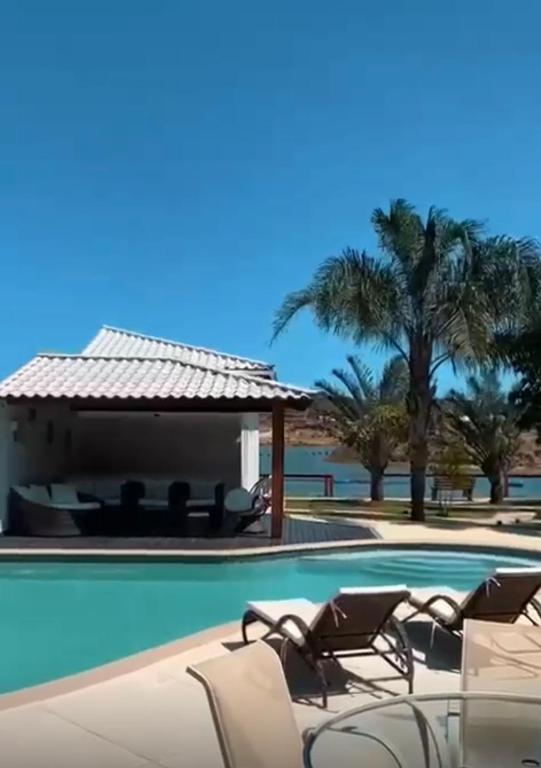 a pool with chairs and a gazebo and palm trees at Búzios Mansion Canal Area in Búzios