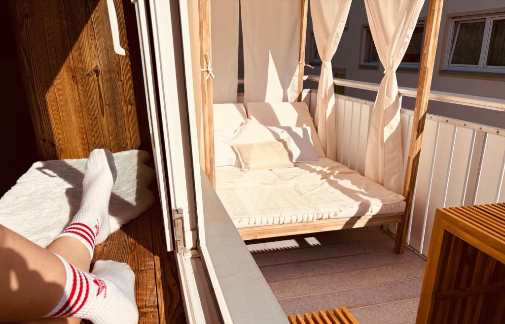 a person in white socks standing on a porch with a swing at Alpen Erlebnis Oberstaufen in Oberstaufen