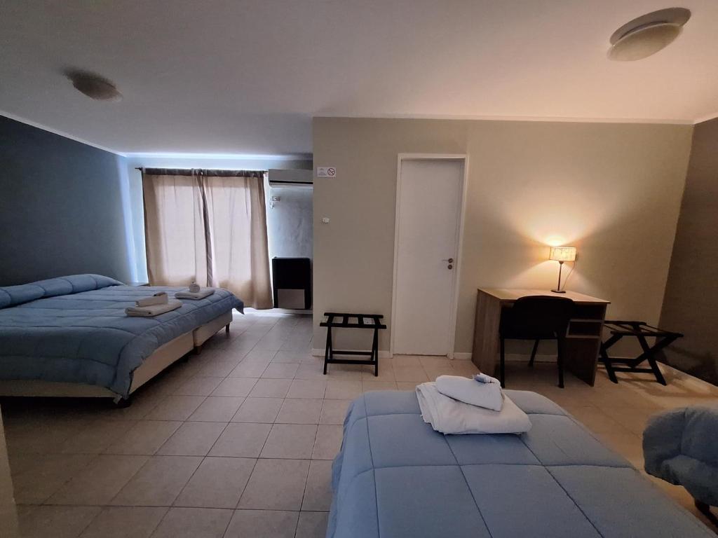 una camera da letto con due letti, una scrivania e un tavolo di El Portal Hoteles y Aparts a Rincon de los Sauces