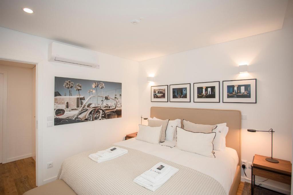 a white bedroom with two beds and pictures on the wall at Liiiving in Gaia - Cooper Residence Apartment II in Vila Nova de Gaia