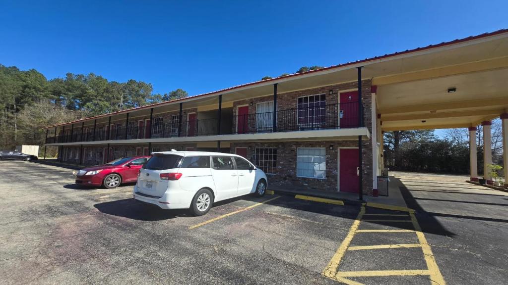 a white car parked in a parking lot in front of a building at OYO Jeffersonian Motor Inn in Prentiss
