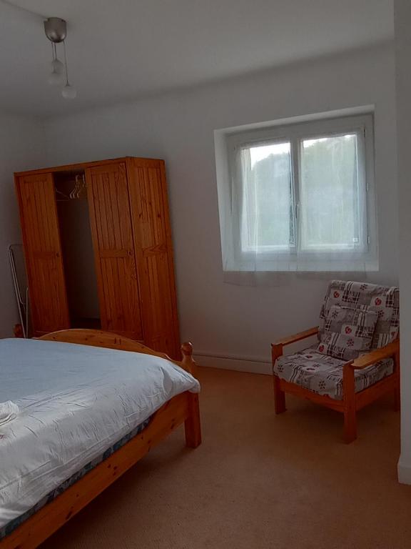 a bedroom with a bed and a chair and a window at Gîte les coquelicots côté jardin in Morbier