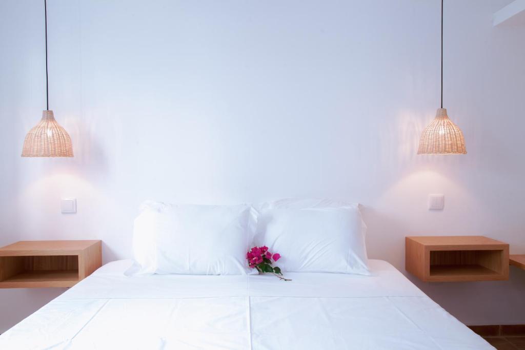 a white bed with a bouquet of flowers on it at Mar-Ria 1 in Fuzeta