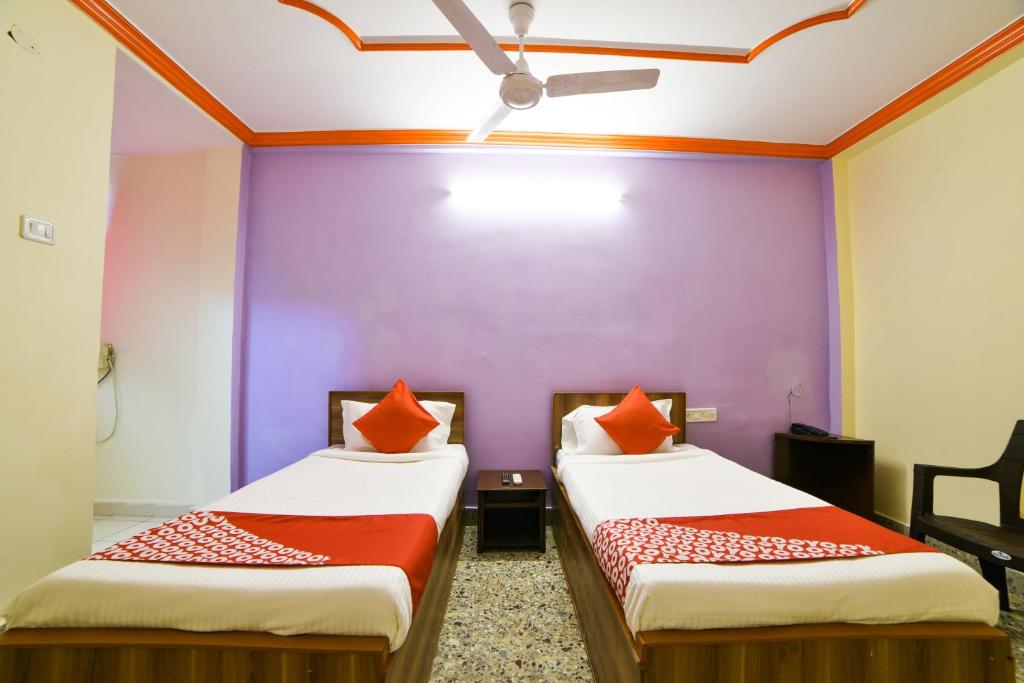 twee bedden in een kamer met een paarse muur bij Hotel O Radika Residency in Warangal
