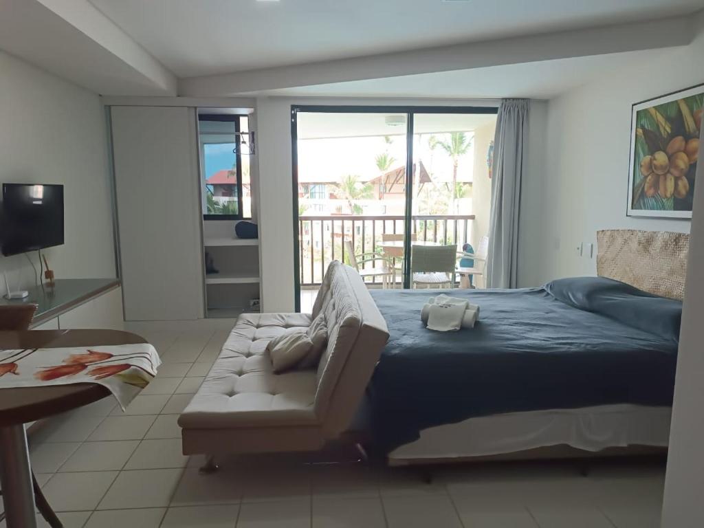 a bedroom with a bed and a couch and a balcony at Estúdio Marulhos, varanda com vista de mar e parque aquático, à beira-mar de Muro Alto, wi-fi, restaurante, estacionamento e a 10' de Porto de Galinhas in Porto De Galinhas
