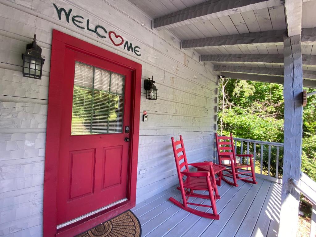 eine rote Tür auf einer Veranda mit zwei roten Stühlen in der Unterkunft Heartwood in Sevierville
