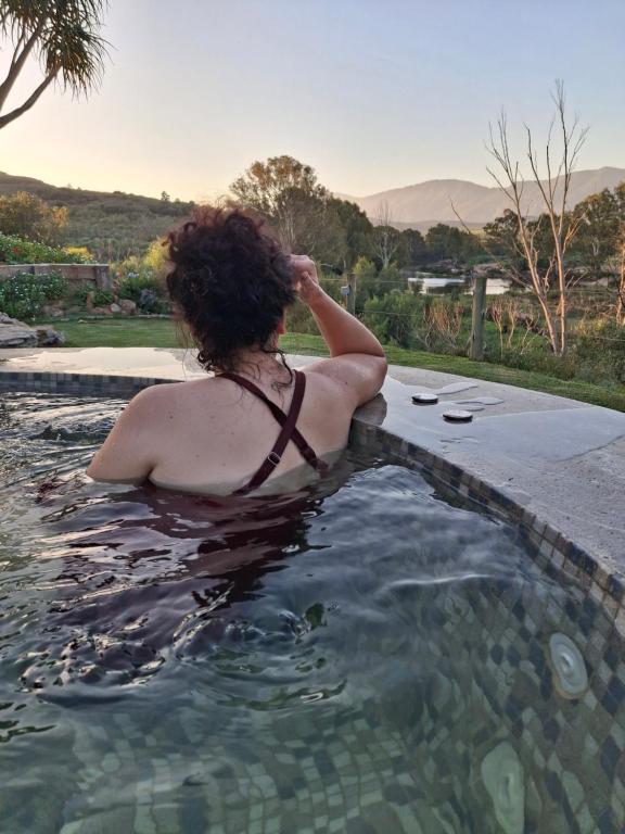 a woman is sitting in a swimming pool at Riverhide, Private Riverside Villa with Jacuzzi & Mountain Views in Bonnievale