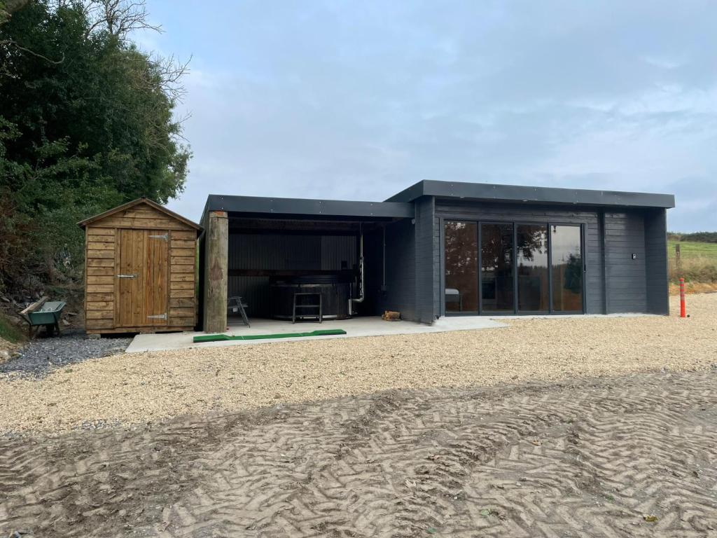 a small black house with a shed in a field at Executive Cabin and Jacuzzi 2 in Monaughrun Cross Roads