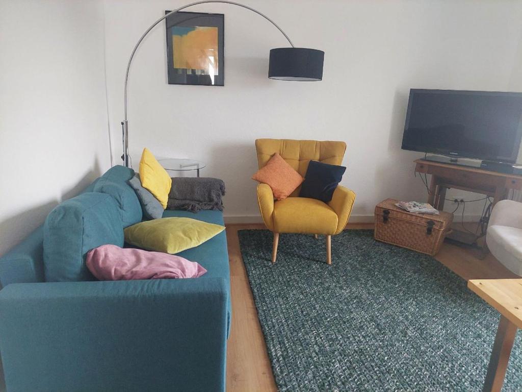 a living room with a blue couch and two chairs at Ferienwohnung Lojane in Kranenburg