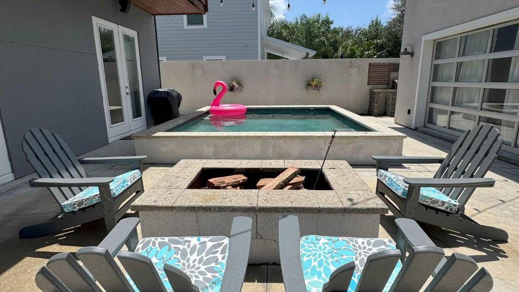 a backyard with a fire pit and two chairs and a pool at Sunkissed Sands in St. Augustine