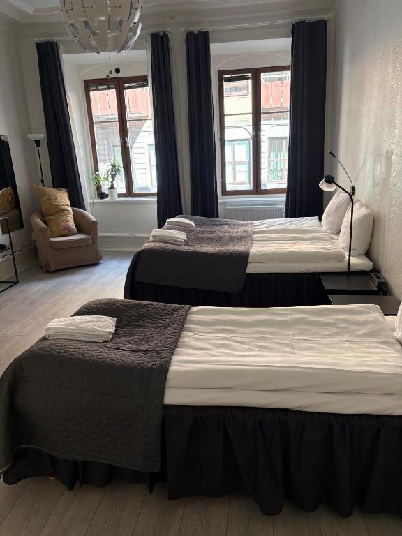 a bedroom with three beds and a chair and windows at Hotel Lemonade in Gothenburg