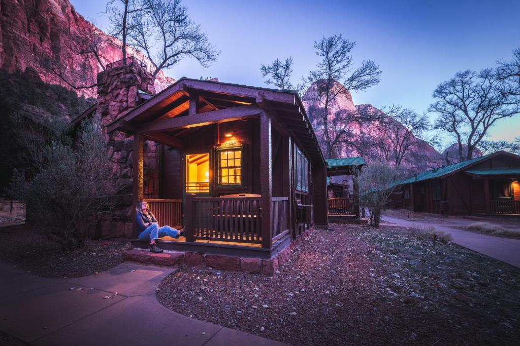 a woman sitting on the porch of a tiny house at Zion Lodge - Inside the Park in Springdale