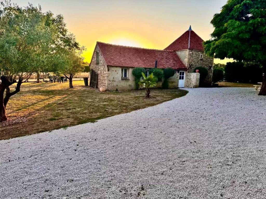 an old stone church with a sunset in the background at Charme ancien pigeonnier au cœur de la campagne in Ourouer-lès-Bourdelins