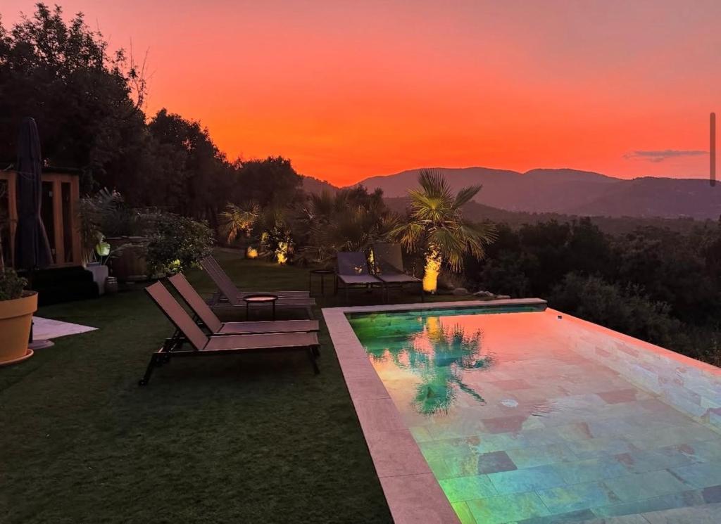 a swimming pool with a sunset in the background at La louva in Les Brugassières
