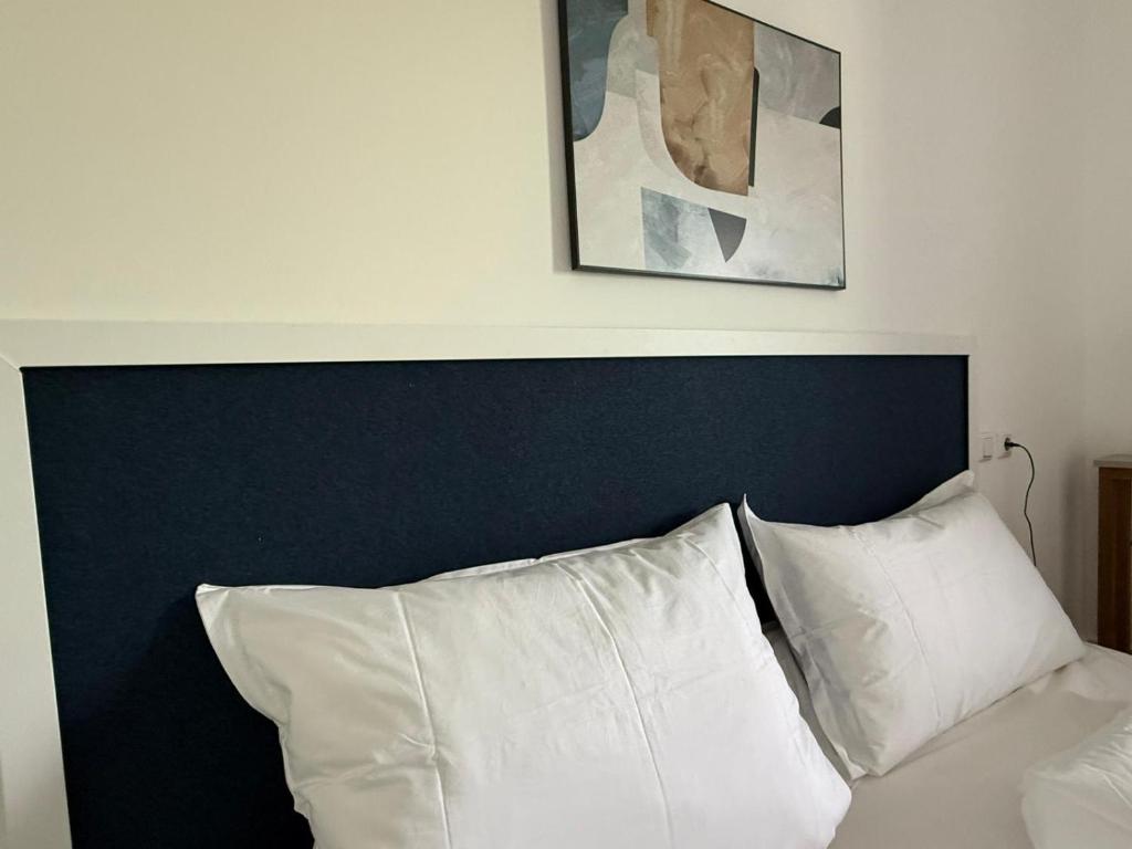 Una cama con almohadas blancas y una pintura encima. en Appartement bis 3 Personen gehobene Ausstattung, en Bad Münder am Deister