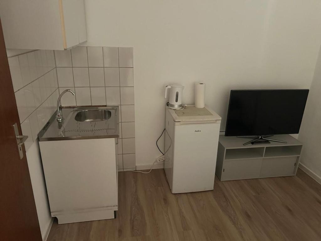 a small kitchen with a sink and a television at Hotelshausbückeburg in Bückeburg