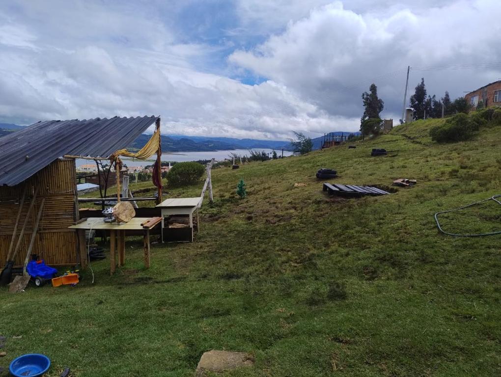 a house on a grassy hill with a table at Zona de camping zoe in Guatavita