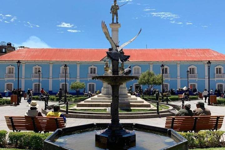 ein Brunnen vor einem Gebäude mit Menschen, die auf Bänken sitzen in der Unterkunft Central Flat Cusco - Walk to Main Plaza in Cusco