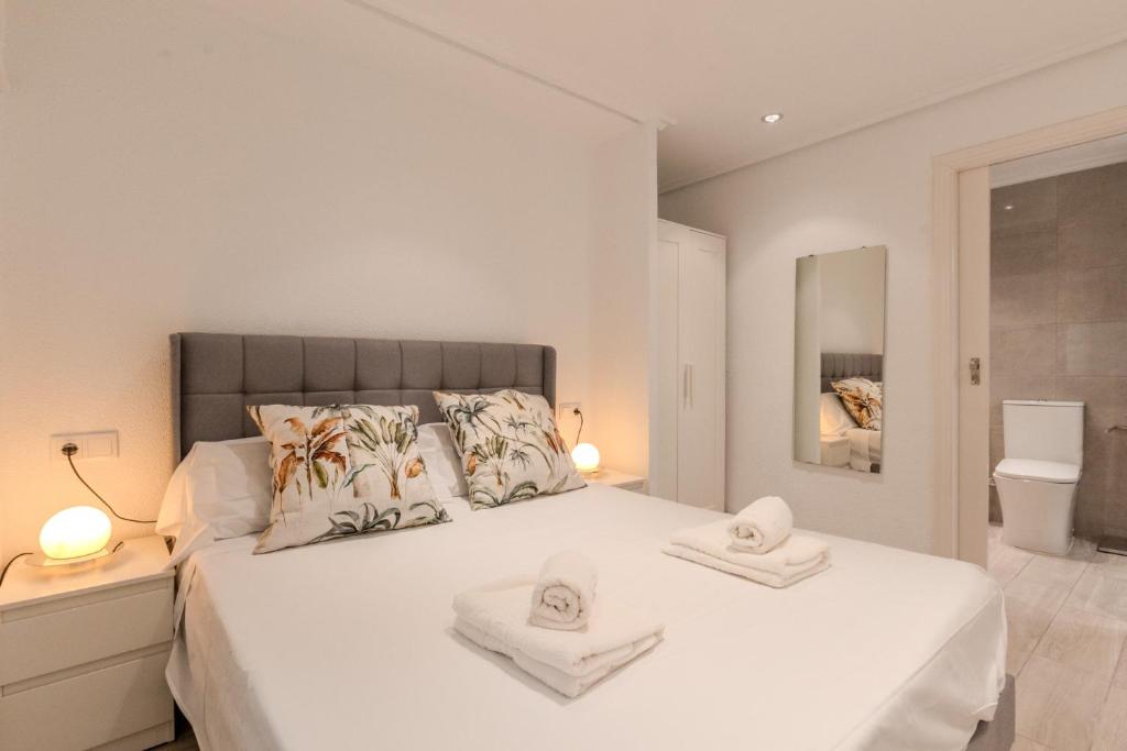 a bedroom with a white bed with towels on it at Downtown apartment near the beach and airport in Santa Pola
