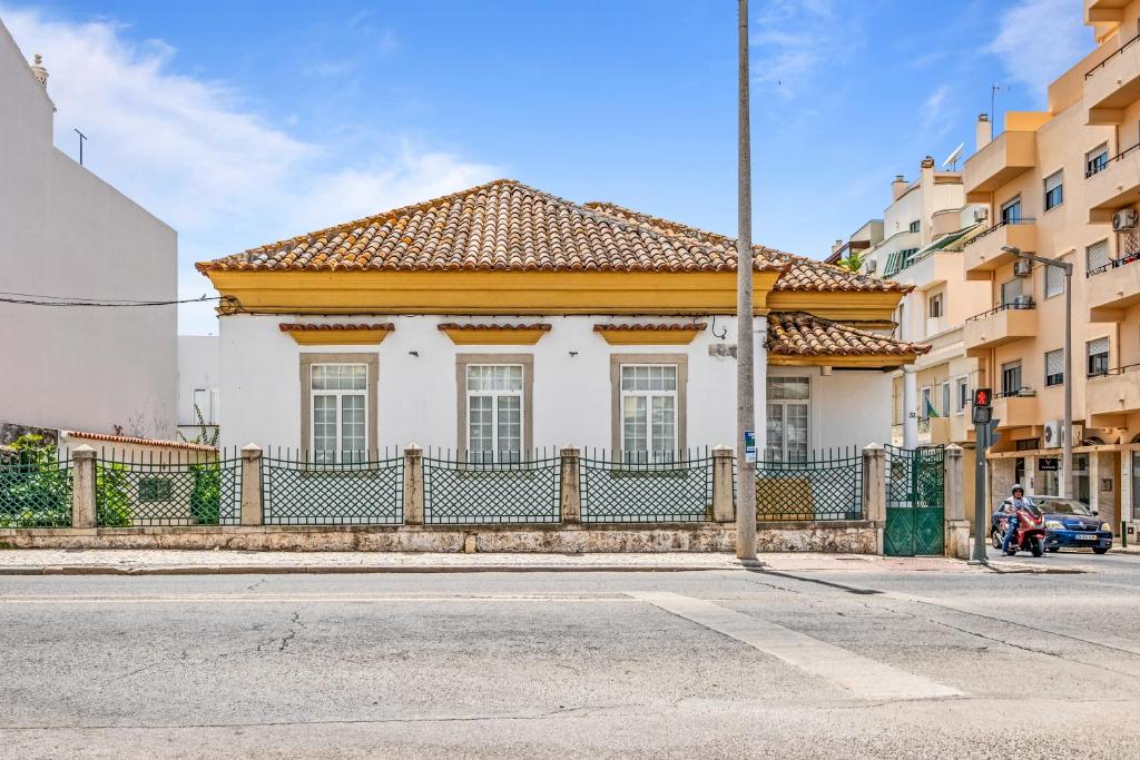 ein weißes Haus mit einem Zaun vor einer Straße in der Unterkunft Plaza Inn Hostel & Rooms in Faro