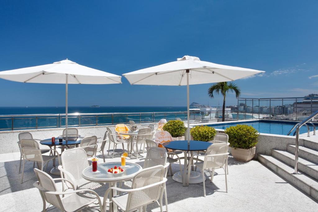 patio ze stołami i białymi parasolami oraz oceanem w obiekcie Windsor Palace Copacabana w mieście Rio de Janeiro