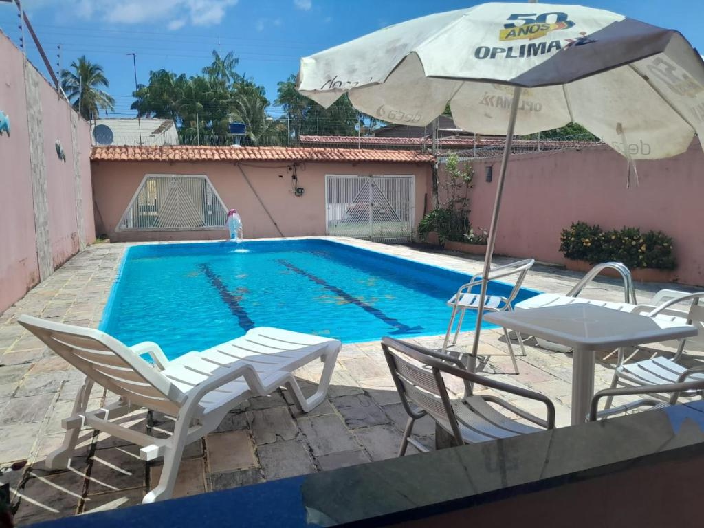 ein Swimmingpool mit Stühlen und einem Sonnenschirm in der Unterkunft Casa de Praia Mosqueiro Chapéu Virado in Belém