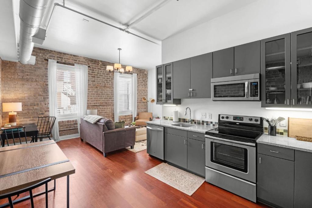 a kitchen with stainless steel appliances and a living room at Downtown Loft- Steps away from Plant Riverside! in Savannah