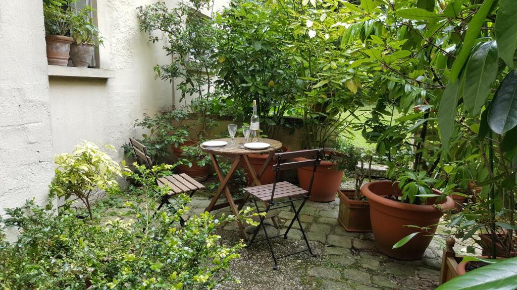 un tavolo e sedie in un giardino con piante di Les Carrés a Versailles
