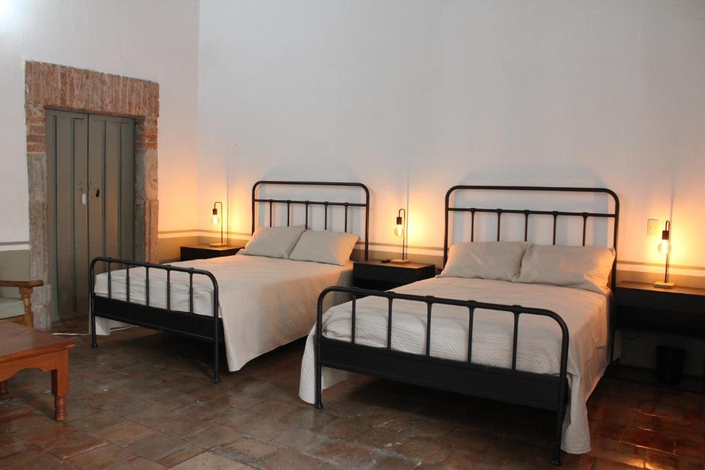 a bedroom with two beds and two tables and lamps at Hospedaje la gran Tenochtitlán in San Martín Hidalgo