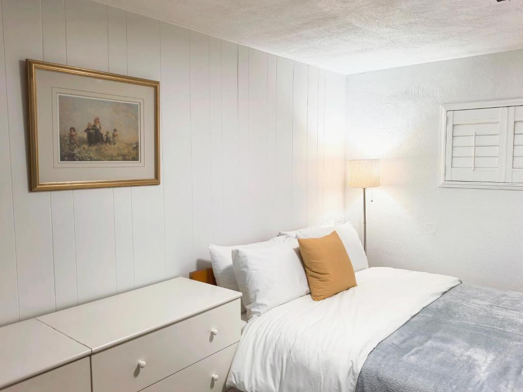 a white bedroom with a bed and a picture on the wall at Private Cozy 2bdrm Sleep5pp Metrotown! Free Parking! Self Check-in! in Burnaby