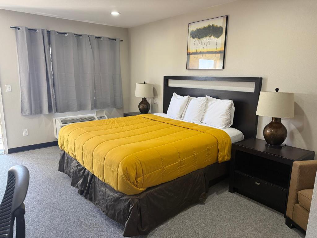 a bedroom with a large bed with a yellow blanket at American Inn & Suites LAX in Inglewood