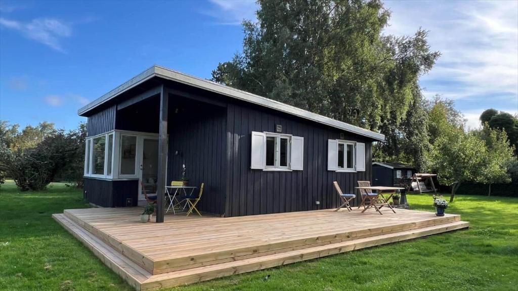 une petite maison noire avec une terrasse en bois dans l'établissement 8171-Praesto-Solsortvej-11, à Præstø
