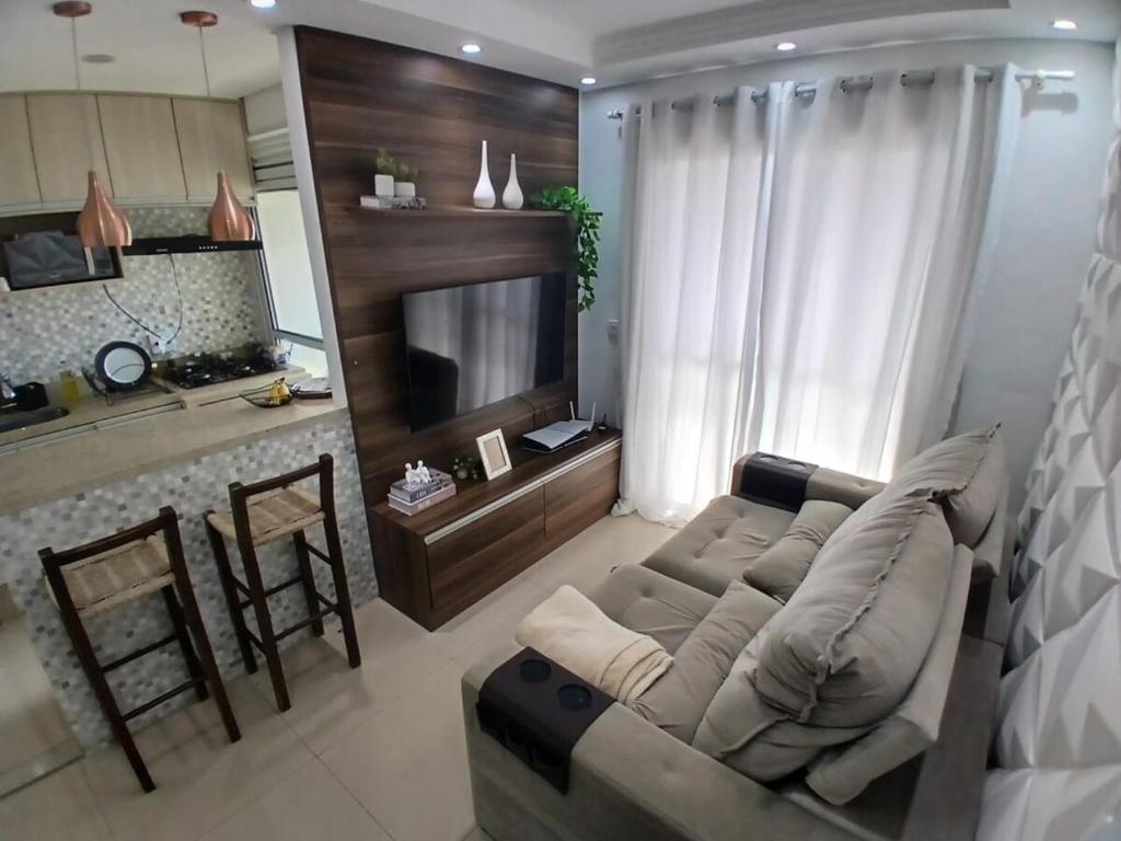 a living room with a couch and a kitchen at Apartamento Familia Granja Viana in Carapicuíba
