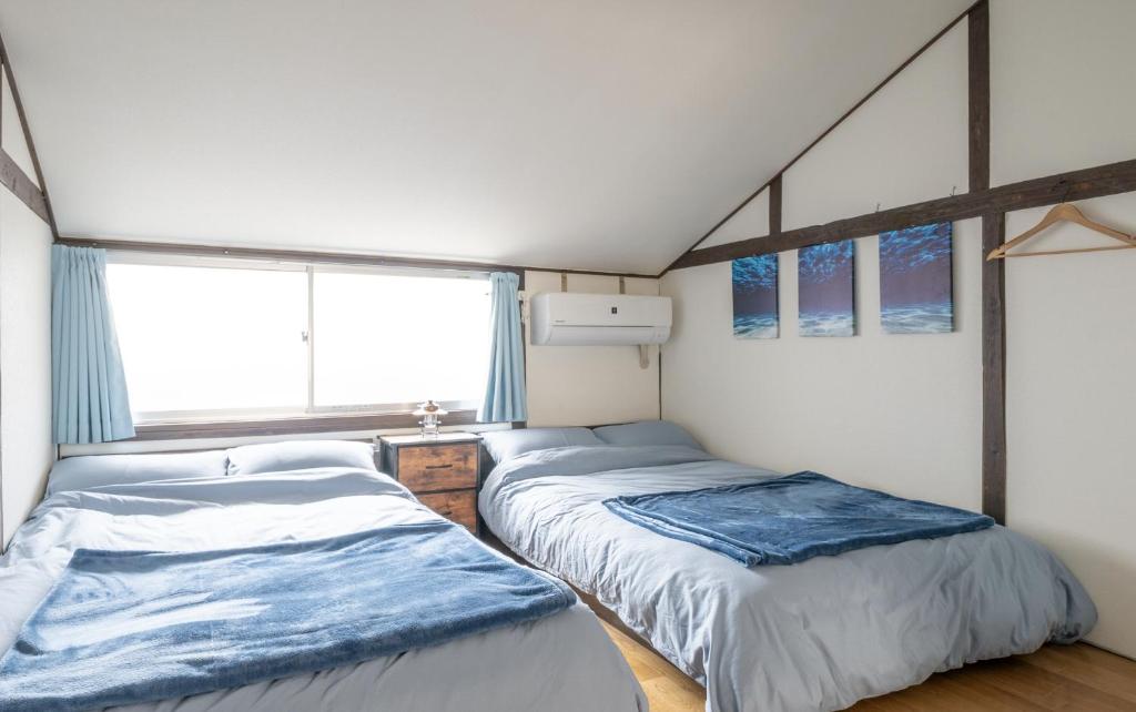 two beds in a room with a window at Atlantis 天下茶屋 in Osaka