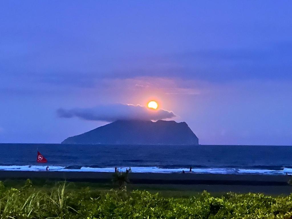 a sun setting over a mountain in the ocean at 遇見龜山島 in Toucheng