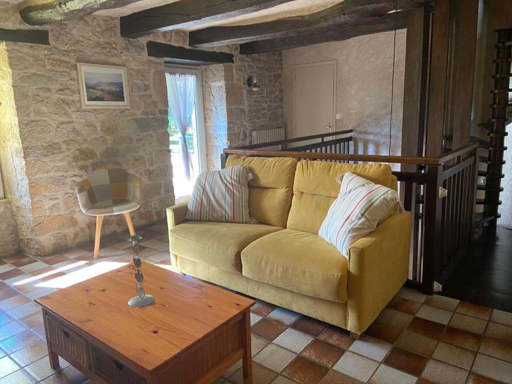 a living room with a yellow couch and a table at Holiday Home in Muret near Château Colombier in Muret-le-Château
