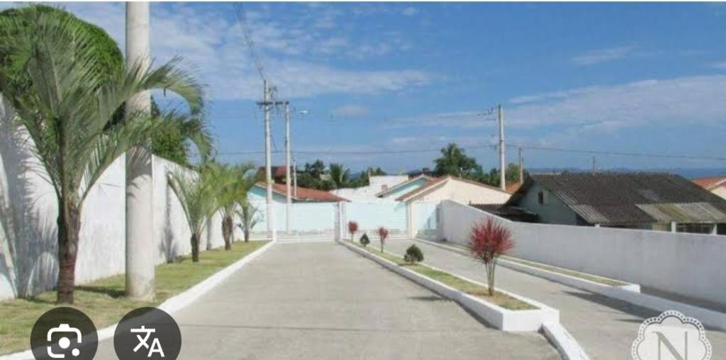 イタニャエンにあるCasa térrea com 2 quartos em Itanhaemのヤシの木と白い建物のある通り