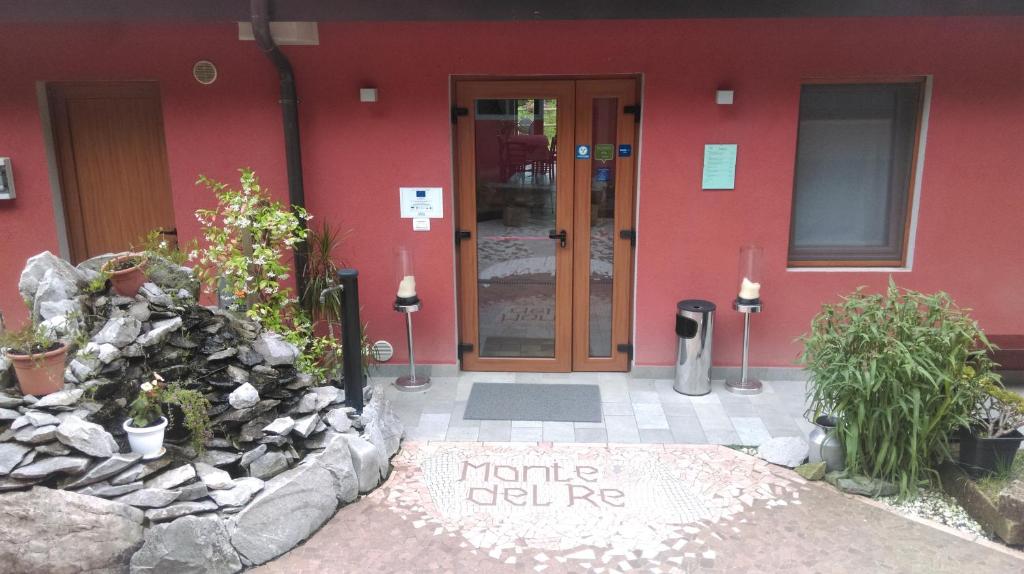 a front door of a red building with a stone wall at Agriturismo Monte Del Re in San Pietro al Natisone